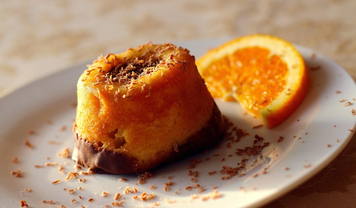 Fatia de bolo de chocolate molhadinho com cobertura cremosa brilhando