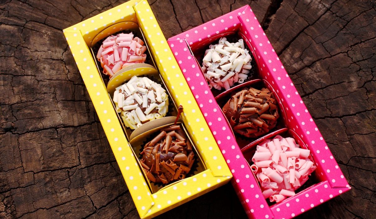 Brigadeiros de morango cor-de-rosa enrolados no açúcar cristal em forminhas de papel