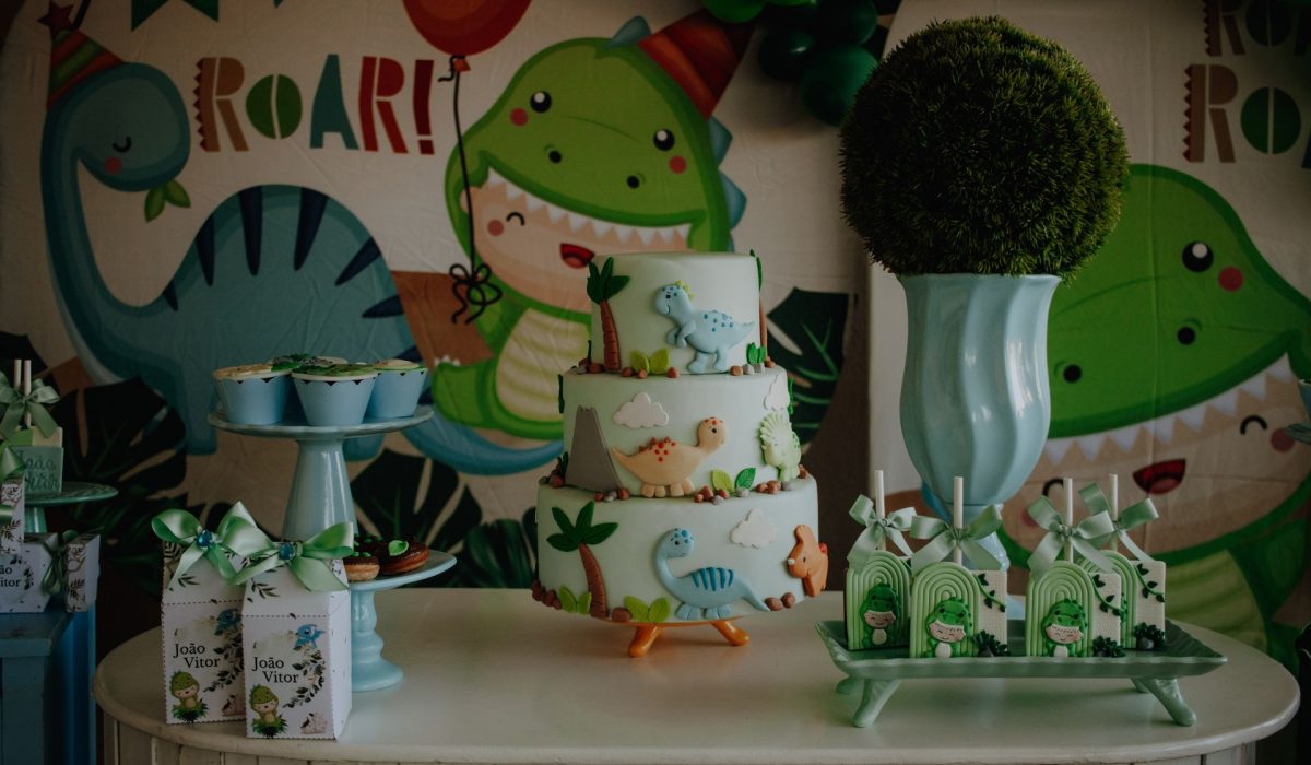 Mesa de doces tema dinossauro com bolo decorado, docinhos e lembrancinhas verdes